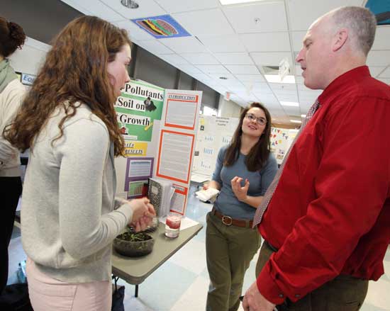 Seniors Alison Ware (left) and Molly Papazian explain their project to Principal Jim O’Shea. The pair took home a prize from the Garden Club of Harvard. 