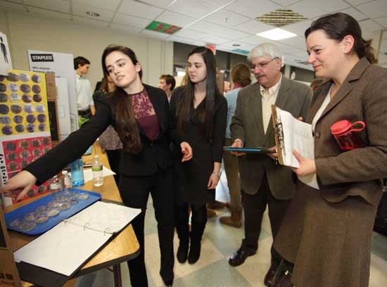 From left: Mackenzie Grant and Stephanie Reeves explain their project, “Bacteria in Bromfield Bathrooms,” to Bill Canning and Linda Dwight. The dirtiest bathroom in the school? The Grade 6/7 Boys’ science bathroom, according to the data