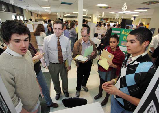 From left: Mitch Williams speaks with judges Scott Pierce, Jim Adelson, and Asha Ramakrishna as classmate D’vonne Williams waits to jump in as the seniors discuss their project, “Testing the Longevity of DNA.”