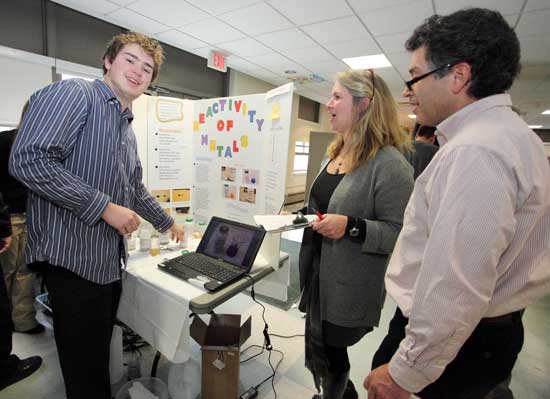 Junior Charlie Friedrich explains his experiment “Reactivity of Metals,” to school committee member Kirsten Wright and her husband, Dan D’Amore. Friedrich took home a prize from the Lions Club.