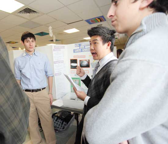 From left: Nick George, Bin Han, and Lucas Hickok tell a judge about their water desalinization project. The group later won an award from the Parent Teacher Organization.  