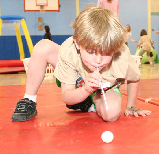 Baylor Ashe chases a ping-pong ball across a mat during a field day relay race.