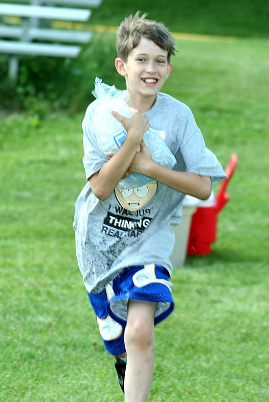 Keiran Dean carries a bag of ice in a relay race.