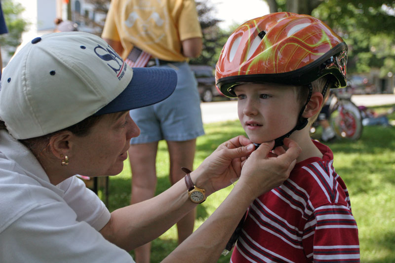 David Latham gets fitted for a bike helmet by firefighter Oona Aldrich. The fire department passed out helmets and educated about safety.