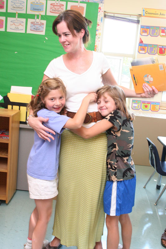 First-grade teacher Patricia Conway gets an enthusiastic hug from former students Kelly Pickreign and Cameron Hettich.