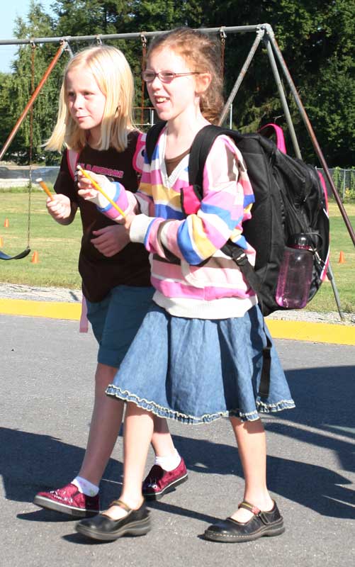 Fourth-graders Tess Baucom and Racheal Makosky walk into school holding new pencils given to them by their bus driver.