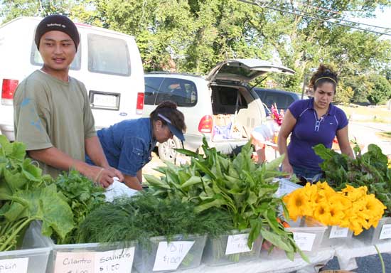 Toulee Hang, Maria Moeira, and Stefanie Moreira set up produce from the Hmong farms at Bolton Flats.