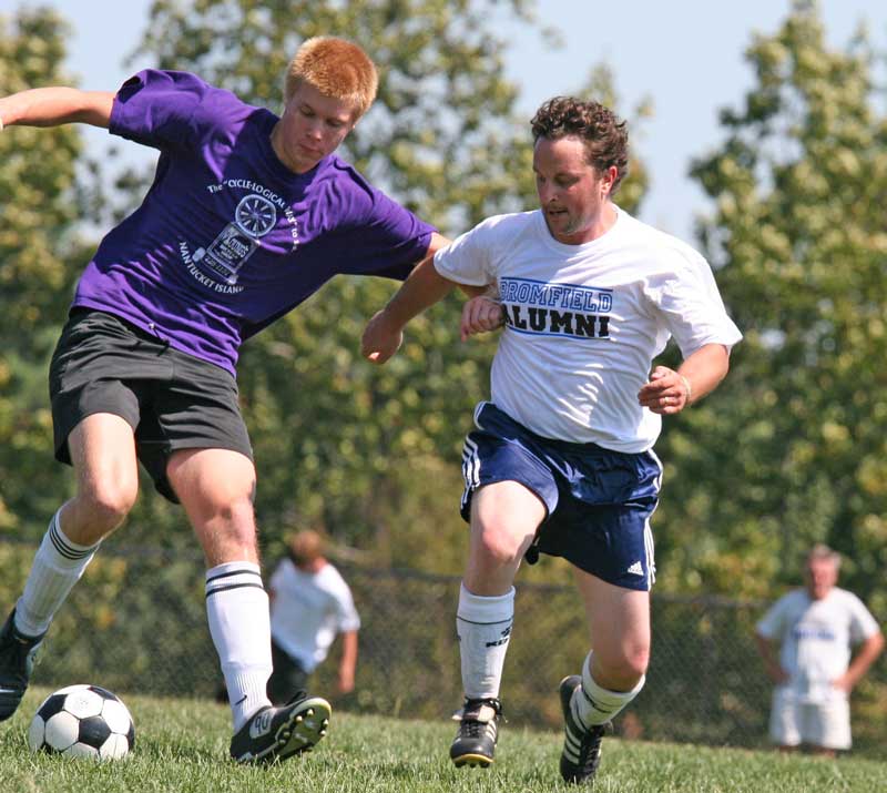 Bromfield Trojan Conor Kempton tries to keep the ball away from alumni opponent Mike Gutlzer.
