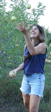 Linda Hoffman juggles homegrown organic apples in her orchard. (Photo by Lisa Aciukewicz)