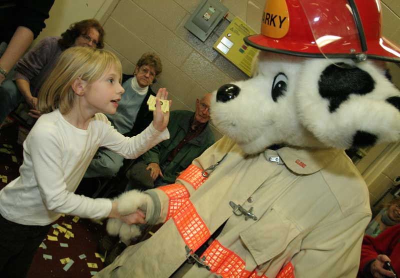 Kayla Johnston, granddaughter of Paul and Doris Johnston, greets Sparky the fire dog.