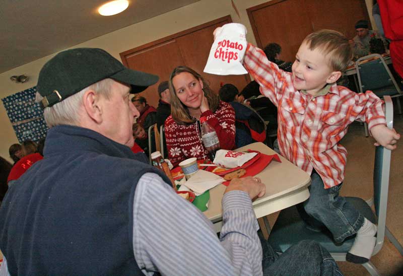 David Dyer (left) pretends to go after grandson Aidan Long’s potato chips as mom, Andrea Long  watches with amusement during the lunch with Santa.