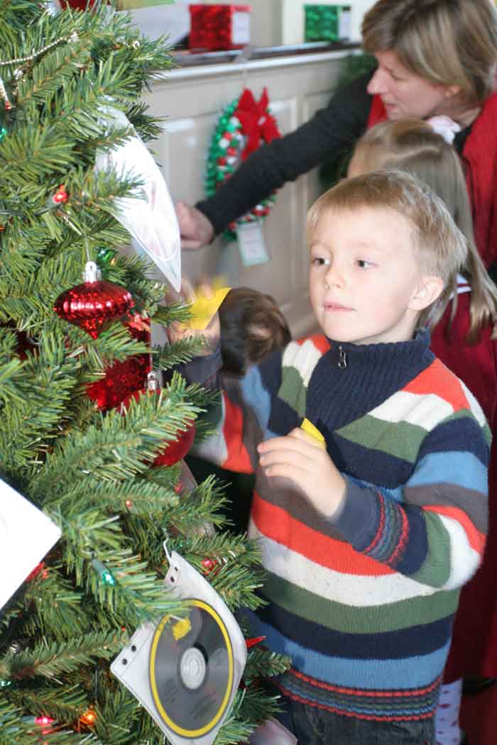 Skyler Clawson, grandson of Dick and Phyllis Clawson checks out the Christmas CDs on one of the many Christmas trees raffled by the Congregational Church