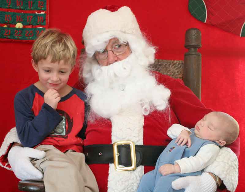Jake Morin listens intently to Santa as baby brother Rowan sleeps through his first lunch with Santa.