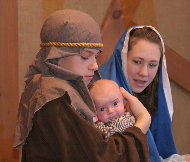 Joseph (Jeremy Buck) holds baby Jesus (Cole Maddelone) as Mary (Jennifer Duckket) looks on.