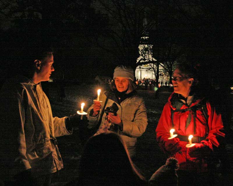 Sean Burns and Leslie and David Neville share candles at the tree-lighting ceremony.