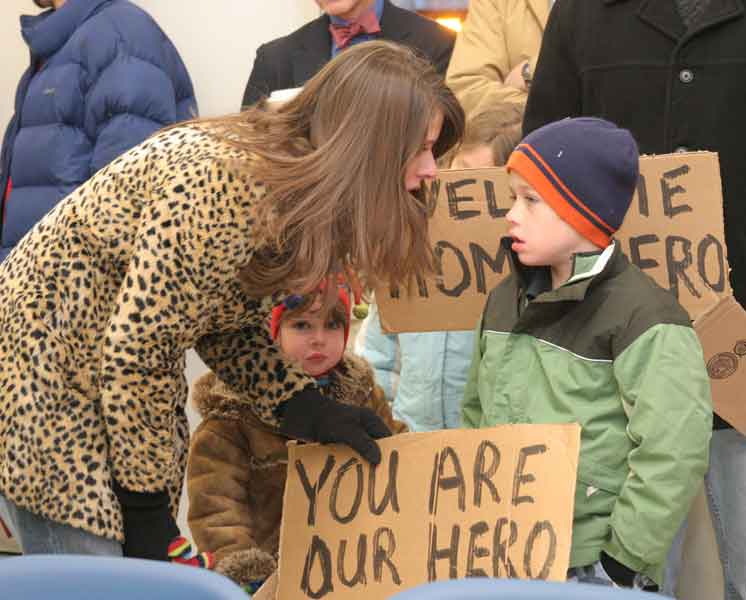 Kristen O’Brien and her children Shea and Braeden hold signs at the homecoming celebration.