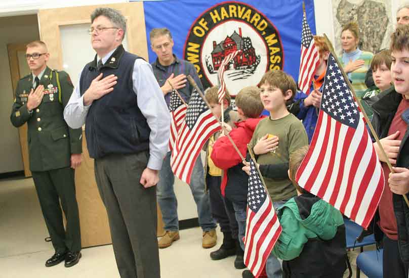 Corporal McClure, Veterans Services Administrator Dennis Lyddy, and many well wishers say the Pledge of Allegiance in a packed Town Hall meeting room.
