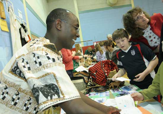 Joseph Kivaa of Kenya stamps passports as Ben Cadman and Karen Shuttle stand by.