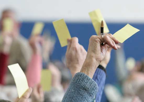 Voters hold their yellow cards in the air waiting to be counted. 