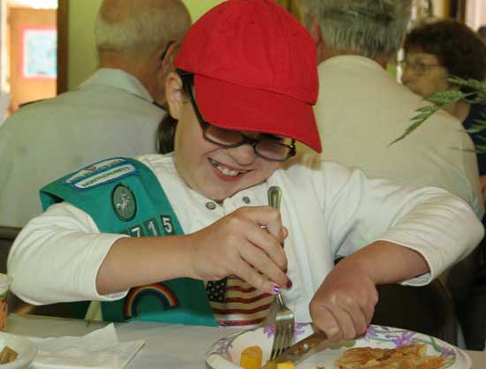 Girl Scout Chase Peters digs into her breakfast at the annual Memorial Day pancake breakfast held by the Unitarian Church to benefit Loaves and Fishes food pantry in Devens.
