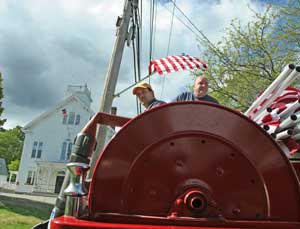 Bill Barton and Bill McElhaney enjoy their perch atop engine 4 as they travel between telephone poles, placing flags to decorate for Memorial Day celebrations. (Photo by Lisa Aciukewicz) 