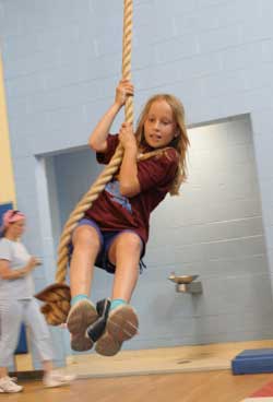 Sarah Seymour prepares to drop a bean bag in a bucket while swinging like Tarzan.