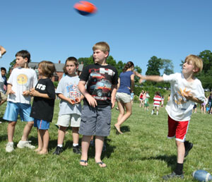 From left: Jonathan Stadler, Nico Agosta, Andrew Hill, and Chris Steffek-Vogel watch to see if Charlie Frost (far right) hits his target in the football toss.