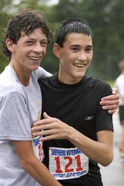 Alex Calderwood, left, hugs Max Flaton after finishing the Great Harvard 5 Mile Road Race. Max won the Under 18 age group and finished 17th overall with a time of 30:58, while Alex finished 22nd with a time of 31:07. Max was the third Harvard resident to cross the finish line and Alex was fourth. (Photo by Ellen Harasimowicz)