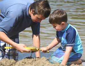 Swimming assistant Carlson Beale helps four-year-old Logan Anderson build a sand castle. (Photo by Lisa Aciukewicz) Swimming assistant Carlson Beale helps four-year-old Logan Anderson build a sand castle. (Photo by Lisa Aciukewicz)