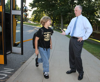 Steppng off the bus, seventh grader Luke Quarles is greeted by Principal Jim O'Shea.