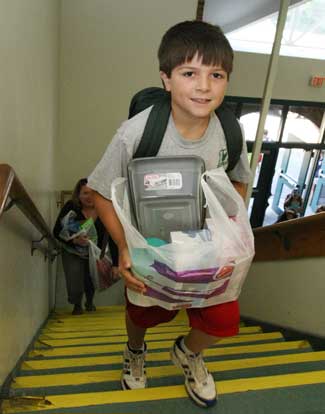 Mikey Brockmann heads up the stairs of the elementary school laden with supplies on the first day of school.