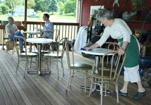 Karen Green wipes down tables as customers enjoy lunch on the porch of Westward Orchards Farm Store. (Photo by Lisa Aciukewicz) Karen Green wipes down tables as customers enjoy lunch on the porch of Westward Orchards Farm Store. (Photo by Lisa Aciukewicz)