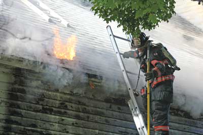 Ayer Captain Timothy Johnston climbs down after breaking through the roof to expose the flames.