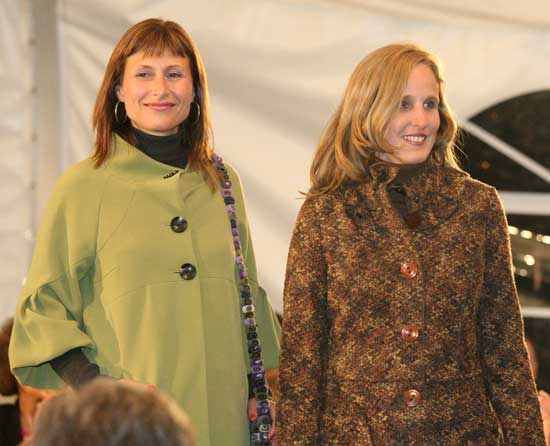 Andra Evans in a moss green jacket by the Kenzie Company poses next to Virginia Justicz in a boucle knit sweater coat by 600 West.