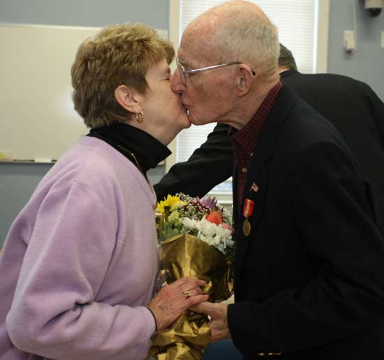 Doris Johnston receives a kiss from husband Paul Johnston as he is recognized for his service and his longstanding role as commander of American Legion Post 119 of Harvard.