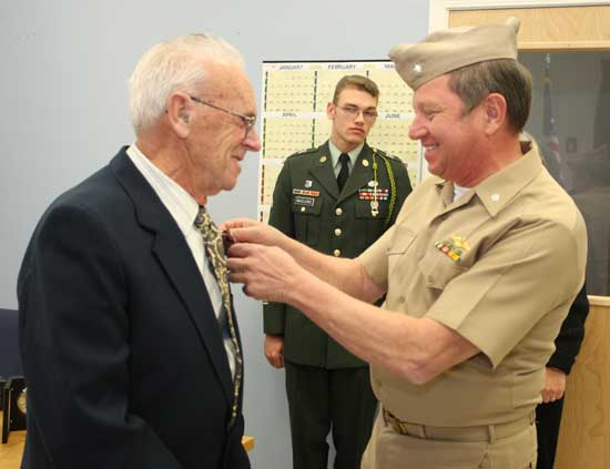 Ron Ricci, selectman and veteran, pins a medal on Amedee Bourgeois’ jacket. John McClure looks on.
