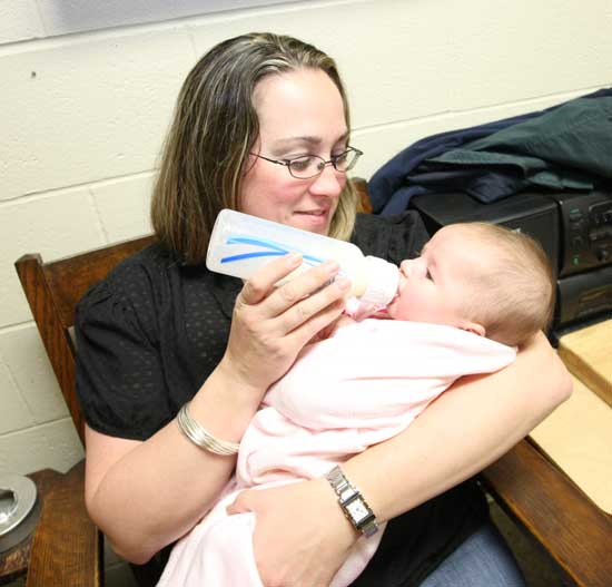 Kim Murphy finds a quiet spot for baby Brianna to enjoy a bottle away from the fray of her first turkey raffle.
