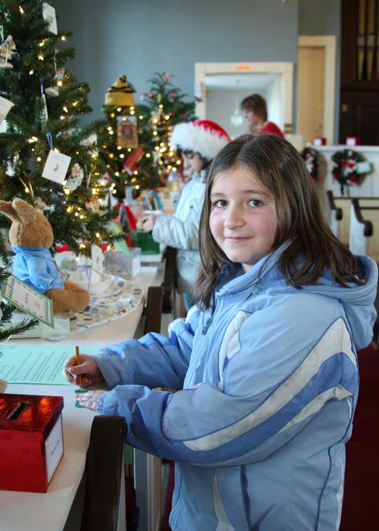 Fourth-grader Courtney Flokos puts her name in for a tree filled with earrings at the Congregational Church Christmas tree raffle.