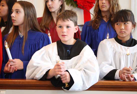 Michaela Nickerson, Nathaniel Dutkewych, and Stacy Nelson hold candles as they sing in the choir.