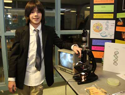 Seventh-grader Sam Zajac poses next to his experiment on extracting DNA from food.
