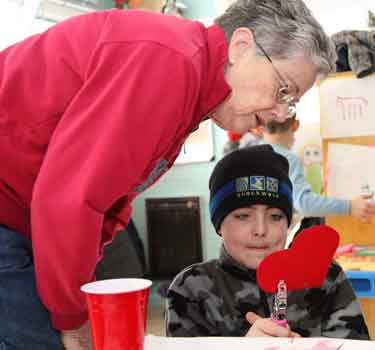 Betty Ashe supervises her grandson, Baylor Ashe, as he tries his hand with a hole punch at the Barn School’s valentine-making event last Saturday.