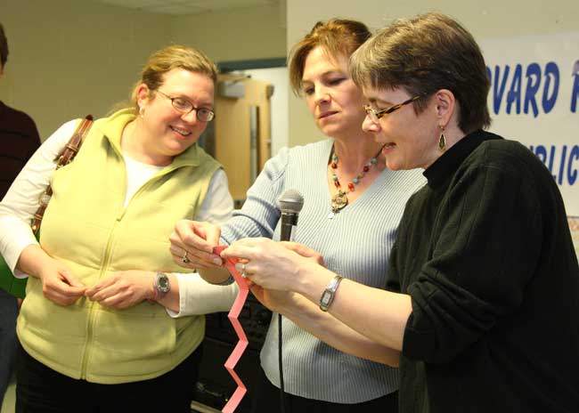 Kathie Jacoby waits as PTO President Katherine Noyes and social studies teacher Kathleen Doherty confirm the family’s winning raffle ticket.
