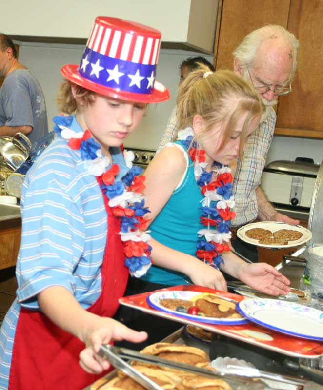 Dan Gordon, Miranda DeGuglielmo, and Otto Solbrig prepare platters of pancakes at the Unitarian Church pancake breakfast.